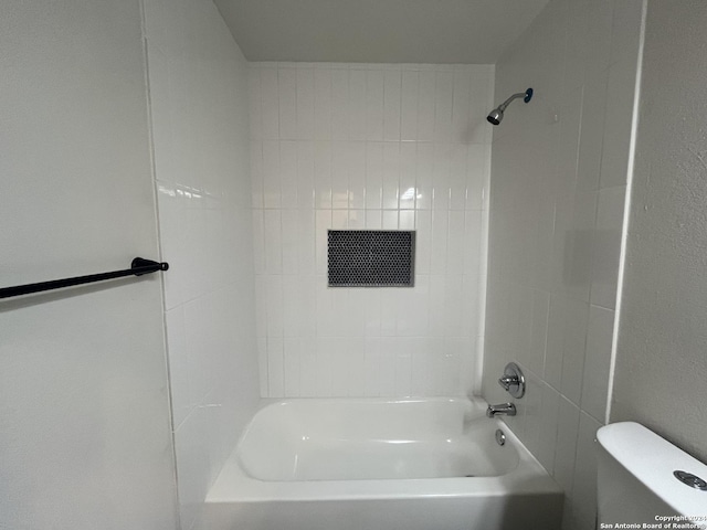 bathroom with tiled shower / bath combo and toilet