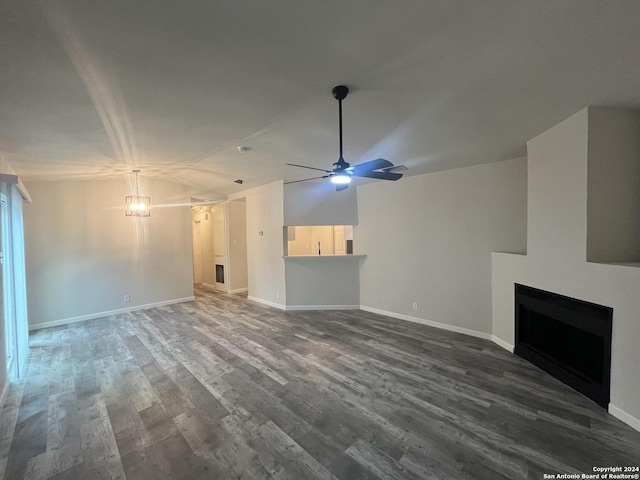 unfurnished living room featuring wood-type flooring, ceiling fan with notable chandelier, and lofted ceiling