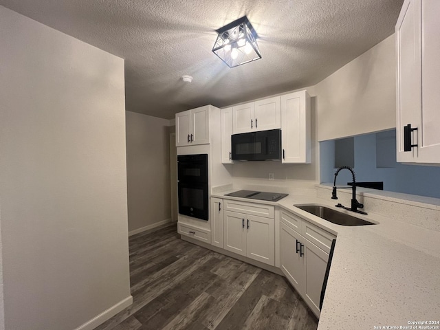 kitchen with dark wood-type flooring, black appliances, white cabinets, sink, and a textured ceiling