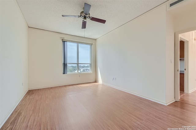 empty room with ceiling fan, light wood-type flooring, and a textured ceiling