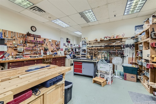 miscellaneous room with a workshop area, a drop ceiling, and concrete flooring