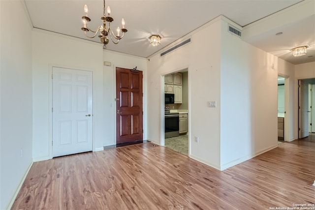 unfurnished room featuring a chandelier, light hardwood / wood-style flooring, and crown molding