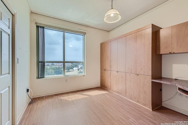 unfurnished bedroom featuring built in desk, a textured ceiling, and light hardwood / wood-style flooring