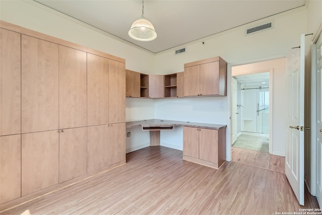 kitchen featuring light brown cabinetry, light wood-type flooring, decorative light fixtures, and built in desk