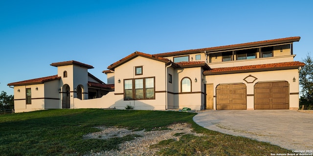 mediterranean / spanish house featuring a garage and a front lawn