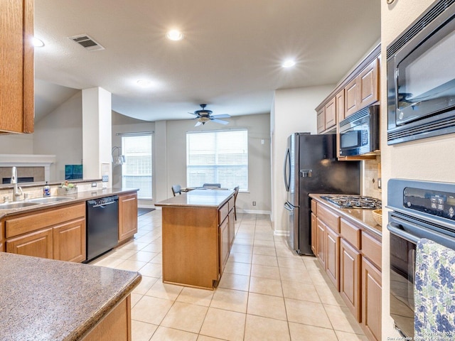 kitchen with light tile patterned floors, stainless steel appliances, a kitchen island, and sink