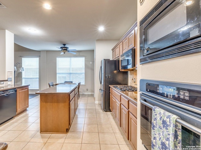 kitchen featuring light tile patterned floors, a kitchen island, ceiling fan, and black appliances