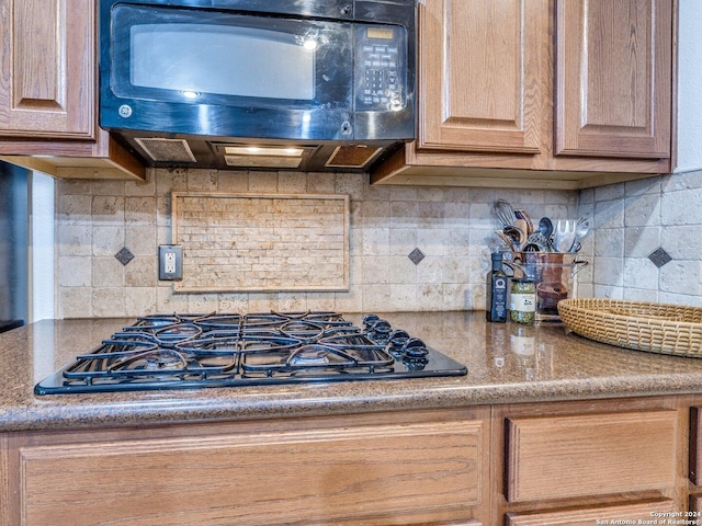 kitchen with stone countertops, gas stovetop, and backsplash