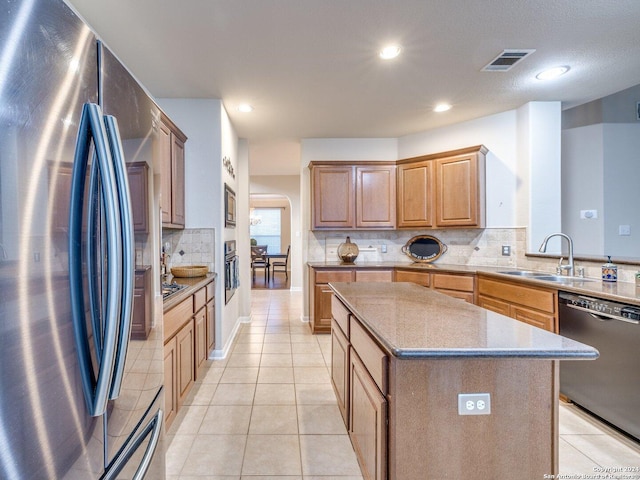 kitchen with backsplash, a center island, stainless steel appliances, and sink