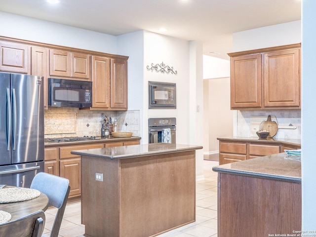 kitchen featuring black appliances, a kitchen island, light tile patterned floors, and backsplash