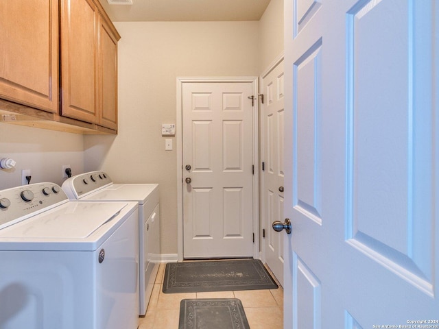 washroom featuring washer and clothes dryer, light tile patterned floors, and cabinets