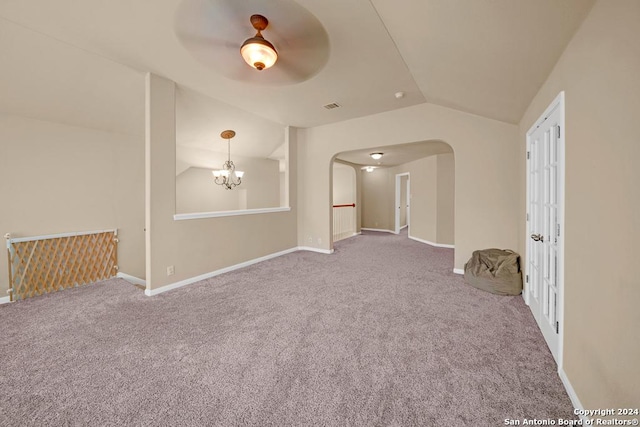 carpeted spare room with ceiling fan with notable chandelier and lofted ceiling