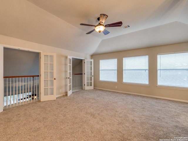 carpeted empty room with ceiling fan, french doors, a healthy amount of sunlight, and vaulted ceiling