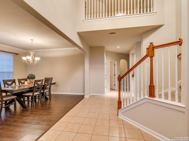 foyer entrance with wood-type flooring, crown molding, and an inviting chandelier