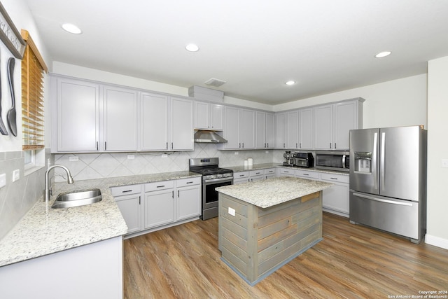 kitchen with a kitchen island, sink, appliances with stainless steel finishes, and light hardwood / wood-style flooring