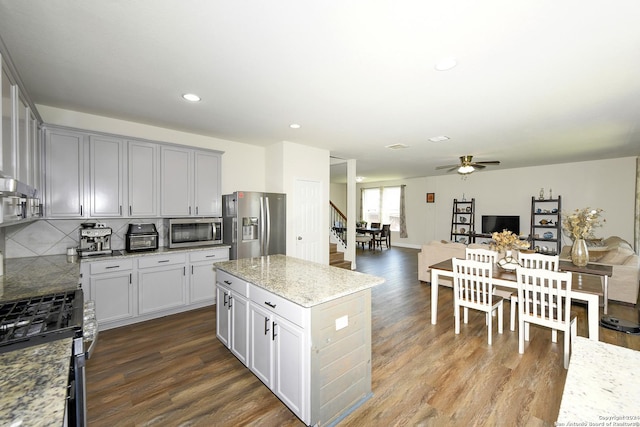 kitchen with tasteful backsplash, light stone countertops, stainless steel appliances, and hardwood / wood-style flooring