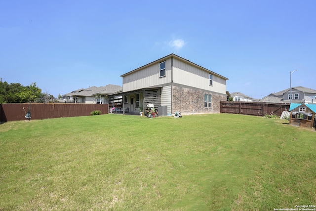 rear view of property featuring a lawn and central AC unit