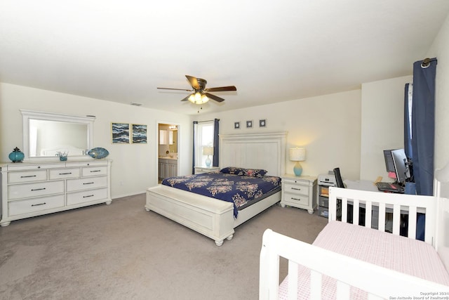 bedroom featuring ceiling fan, light colored carpet, and connected bathroom