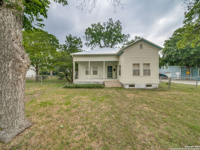 back of house with covered porch and a lawn