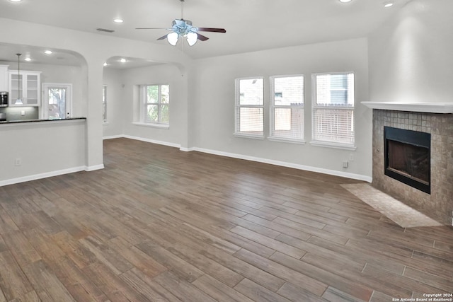 unfurnished living room featuring ceiling fan, a fireplace, and dark wood-type flooring