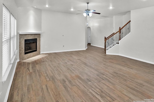 unfurnished living room featuring a fireplace, wood-type flooring, and ceiling fan