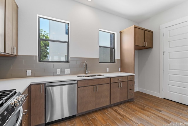 kitchen featuring tasteful backsplash, sink, appliances with stainless steel finishes, and light hardwood / wood-style flooring