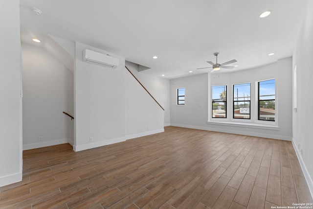 unfurnished living room with hardwood / wood-style floors, an AC wall unit, and ceiling fan