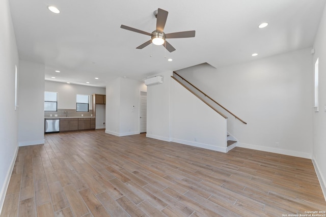 unfurnished living room featuring a wall mounted air conditioner, light wood-type flooring, and ceiling fan