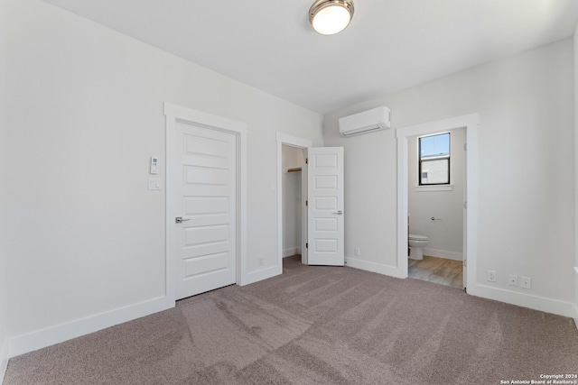 unfurnished bedroom with carpet floors, ensuite bath, and a wall mounted AC