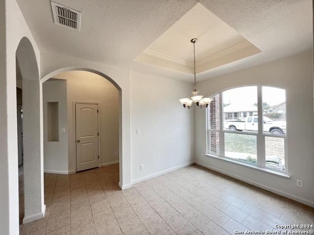 empty room featuring a notable chandelier, a textured ceiling, and a tray ceiling