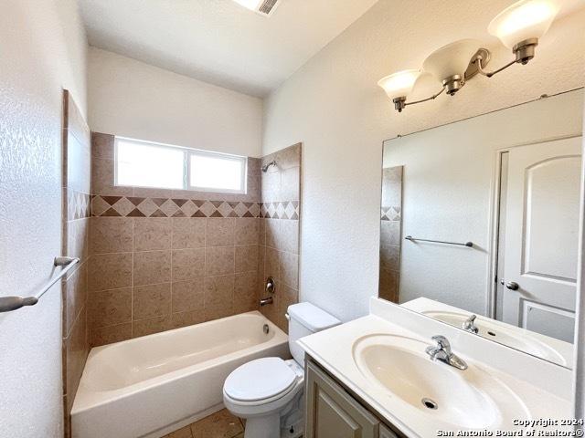 full bathroom with vanity, tiled shower / bath combo, and toilet