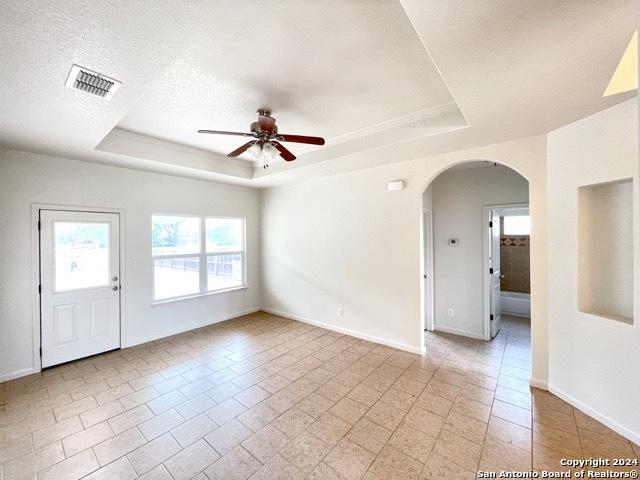 spare room with a textured ceiling, a raised ceiling, ceiling fan, and light tile patterned flooring