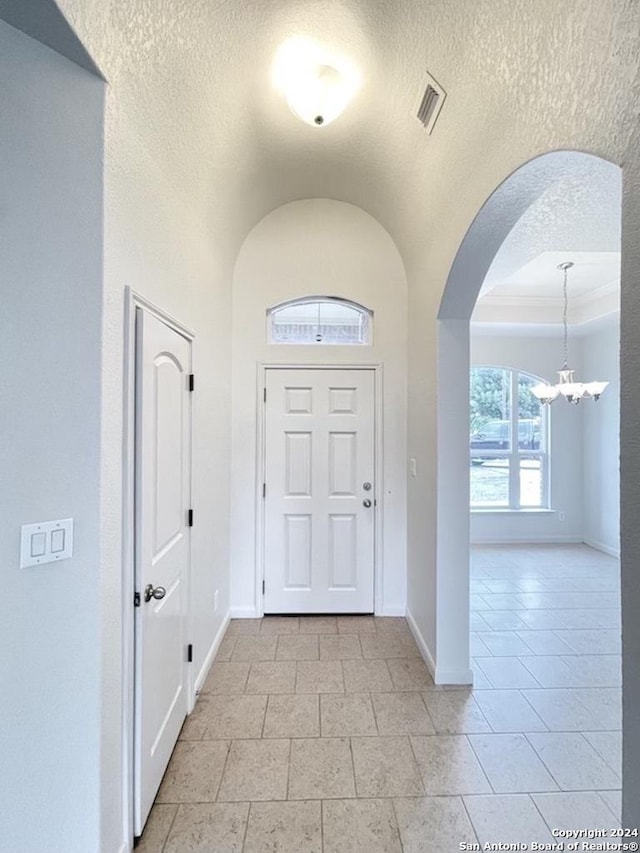 tiled entrance foyer with a notable chandelier and a textured ceiling