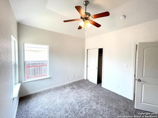 unfurnished bedroom with ceiling fan and dark carpet