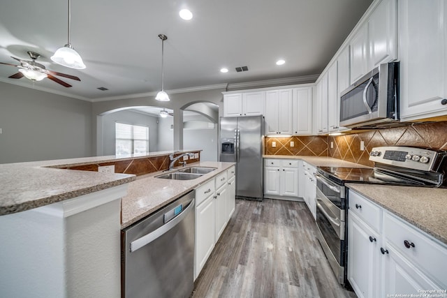 kitchen featuring sink, hanging light fixtures, stainless steel appliances, light stone countertops, and white cabinets