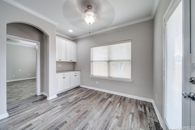 interior space featuring ceiling fan, ornamental molding, and light wood-type flooring