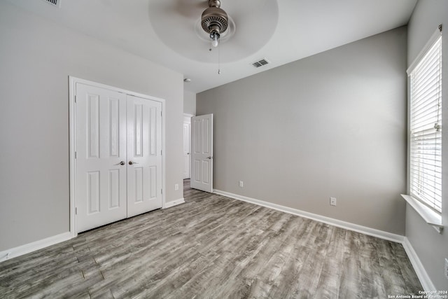 unfurnished bedroom featuring multiple windows, a closet, ceiling fan, and light wood-type flooring