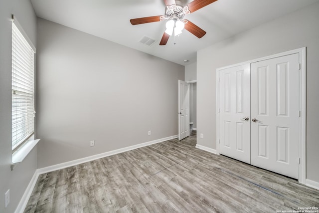 unfurnished bedroom with light hardwood / wood-style floors, a closet, and ceiling fan