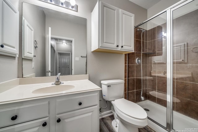 bathroom with vanity, toilet, a shower with door, and hardwood / wood-style floors