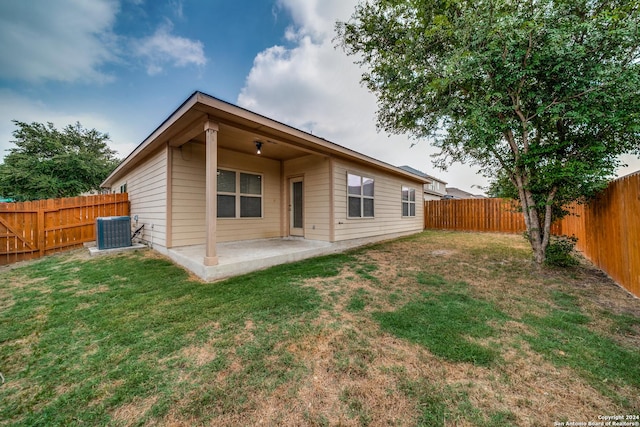 rear view of property with central AC unit, a patio area, and a lawn