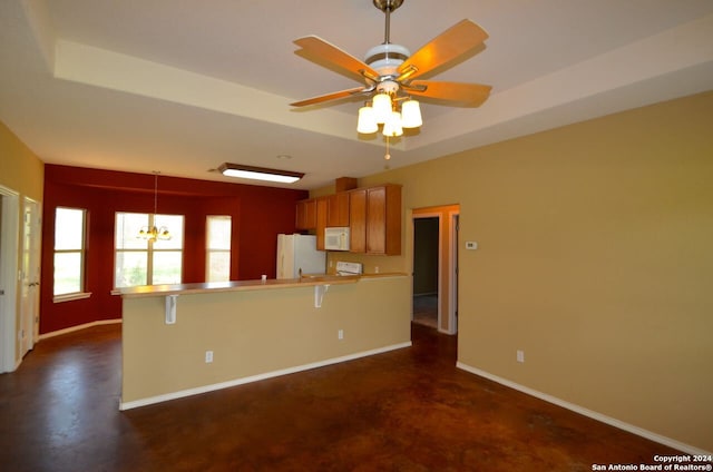 kitchen with ceiling fan with notable chandelier, a tray ceiling, white appliances, a breakfast bar, and pendant lighting