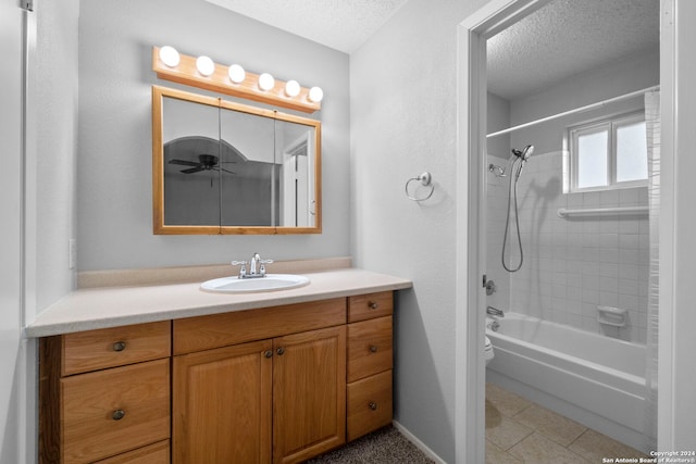 bathroom with tile patterned floors, vanity, a textured ceiling, ceiling fan, and tiled shower / bath