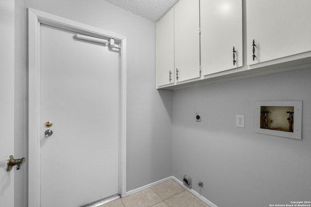 laundry area with cabinets, washer hookup, electric dryer hookup, a textured ceiling, and light tile patterned floors