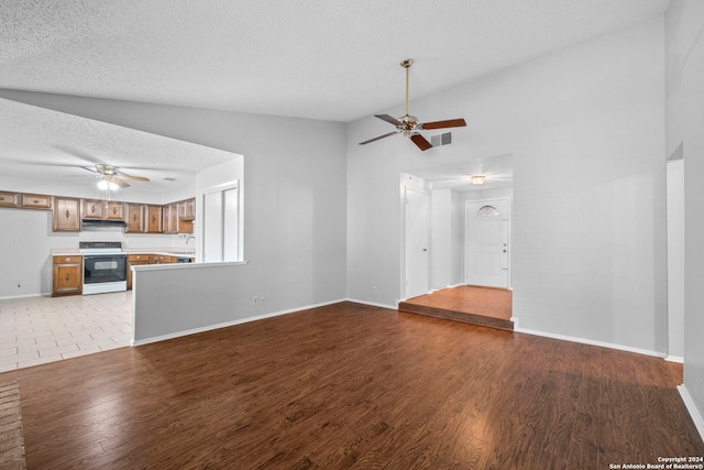 unfurnished living room featuring a textured ceiling, light hardwood / wood-style floors, high vaulted ceiling, and sink