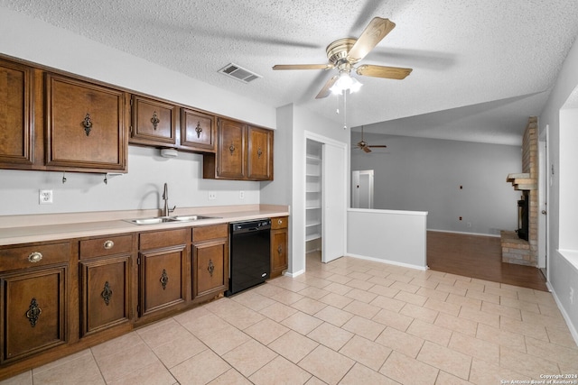 kitchen featuring dishwasher, sink, a textured ceiling, vaulted ceiling, and a fireplace