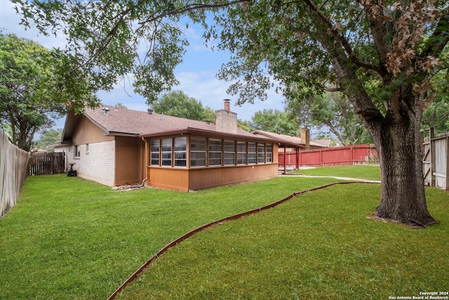 back of property featuring a yard and a sunroom