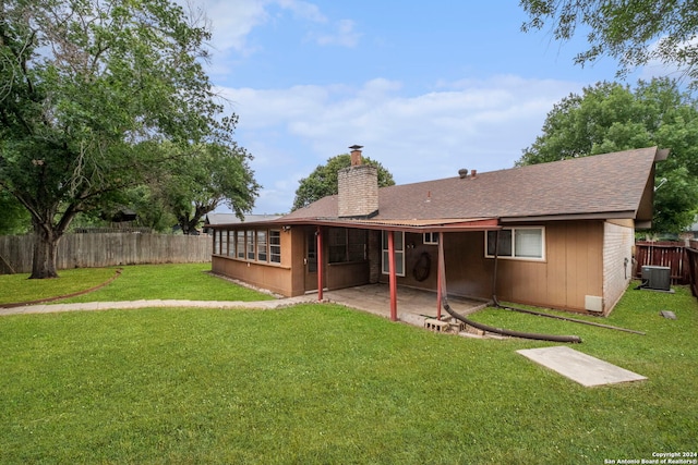 rear view of property featuring a lawn, central AC, and a patio