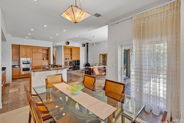 dining space with a wood stove and ceiling fan