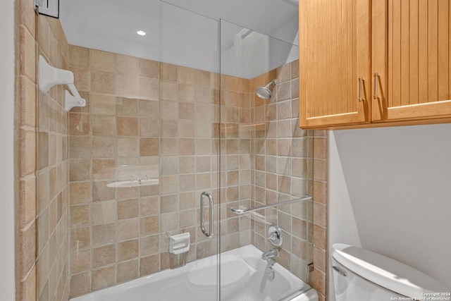 bathroom featuring shower / bath combination with glass door and toilet