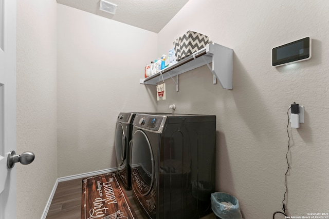 washroom with independent washer and dryer, wood-type flooring, and a textured ceiling